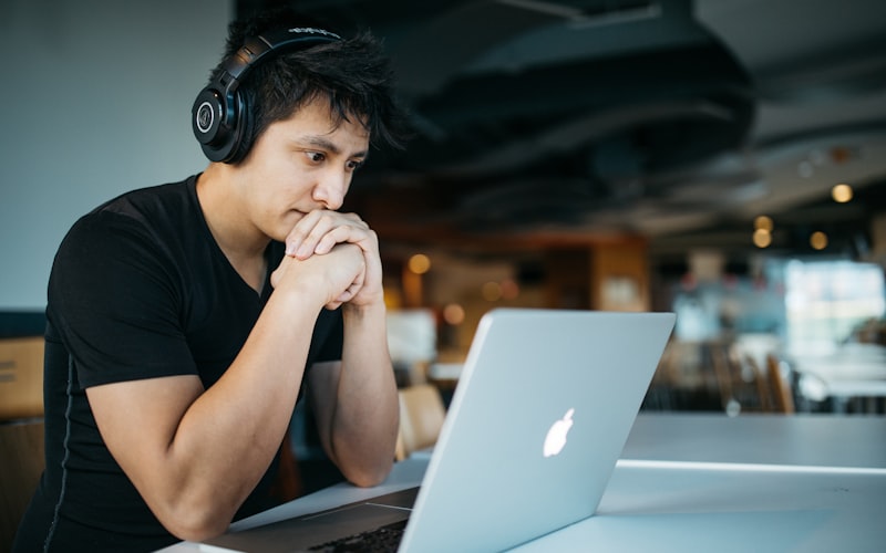 Teen student with headphones focused at a laptop, studying at a desk